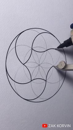 someone is using scissors to draw a circular design on the paper with black markeres