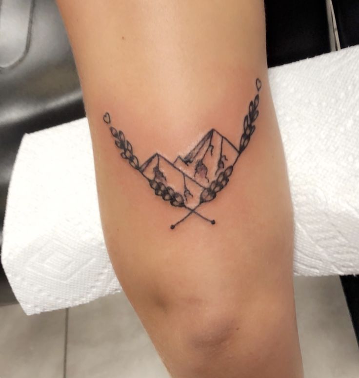 a tattoo on the leg of a woman with mountains in the background and snow capped peaks