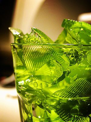 a glass filled with green leaves on top of a table