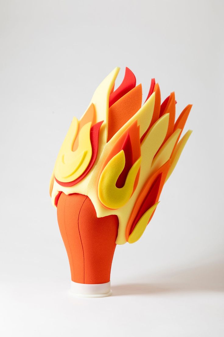 an orange and yellow vase with flames on it's head, against a white background