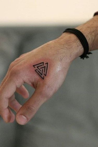 a person's hand with a small triangle tattoo on it