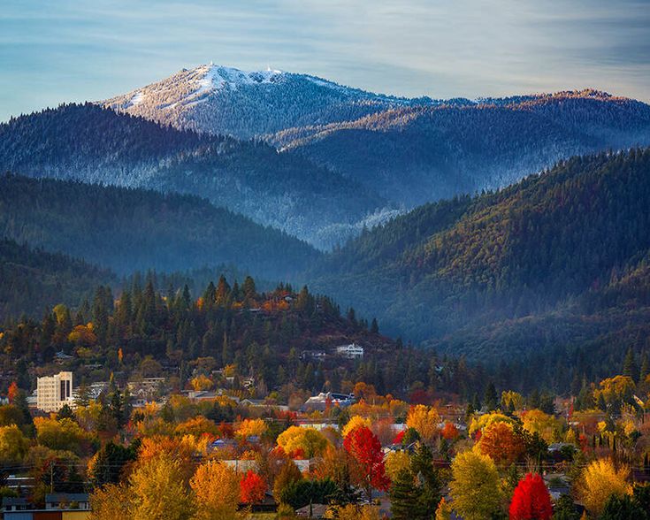 the mountains are covered in snow and fall foliage, as seen from across the valley