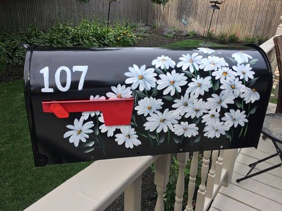 a black mailbox with white daisies painted on it