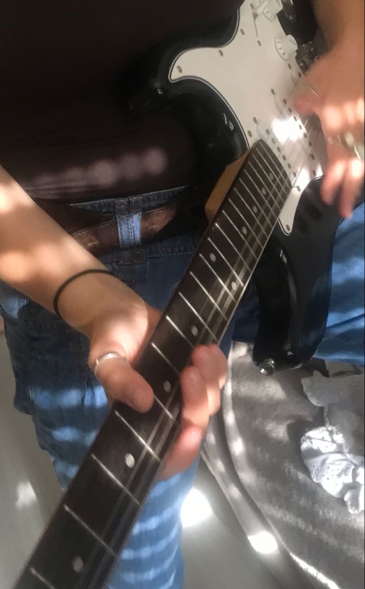 a person holding an electric guitar in their left hand and playing it on the other