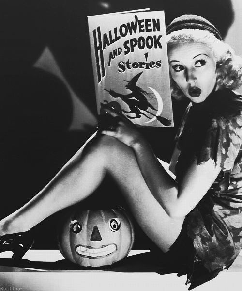 a woman sitting on the floor with a book in front of her and a pumpkin