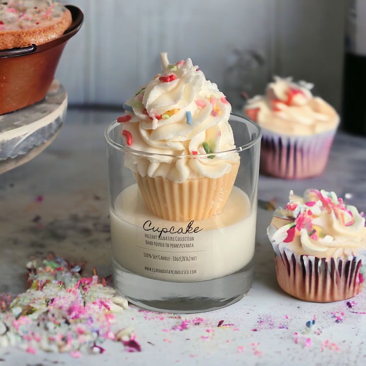 cupcakes with white frosting and sprinkles are on the table