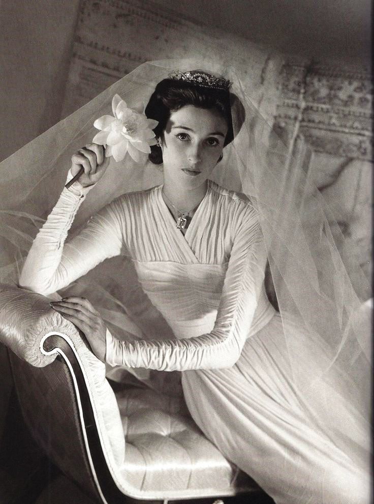 an old black and white photo of a woman sitting on a chair with a flower in her hair