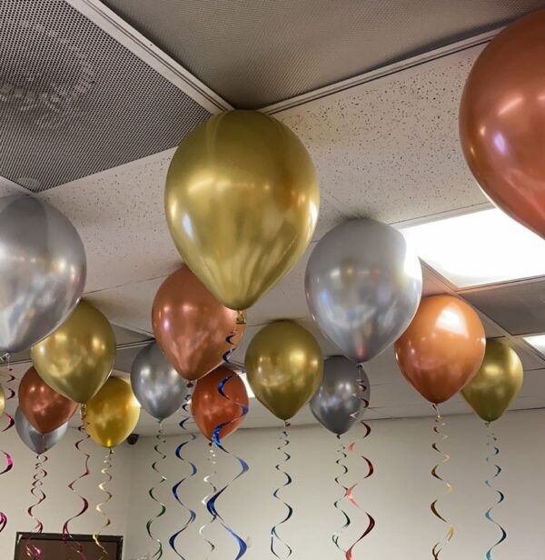 many balloons are hanging from the ceiling in an office setting with confetti and streamers