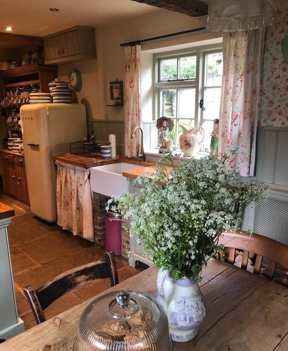 a kitchen with a wooden table and white vase filled with flowers