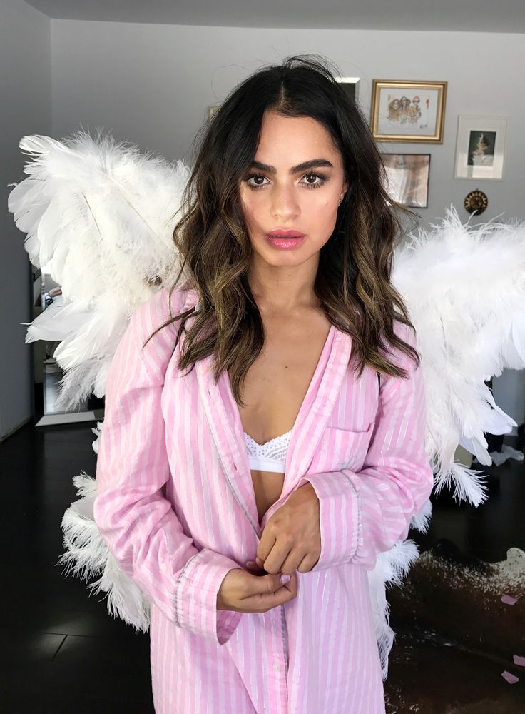 a woman with angel wings on her chest posing for a photo in front of a mirror