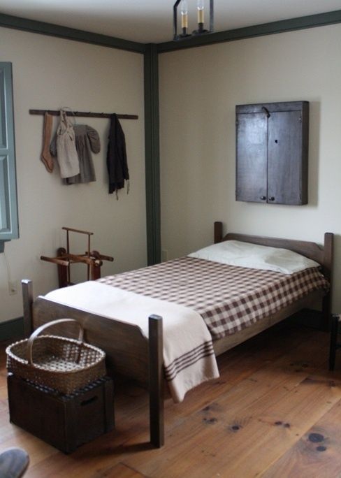 a bedroom with a bed, basket and clothes hanging on the wall next to it