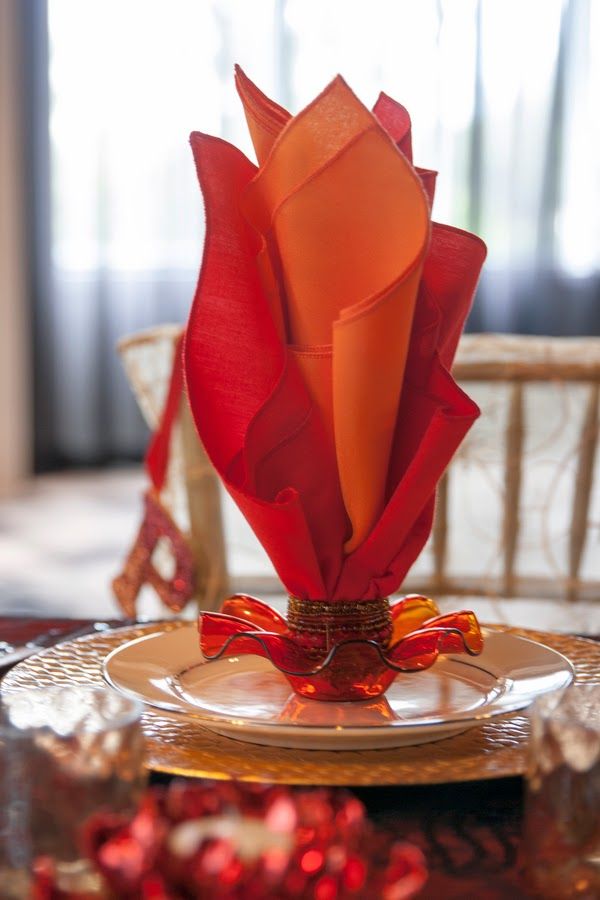 a red rose is sitting on top of a glass plate at the center of a table