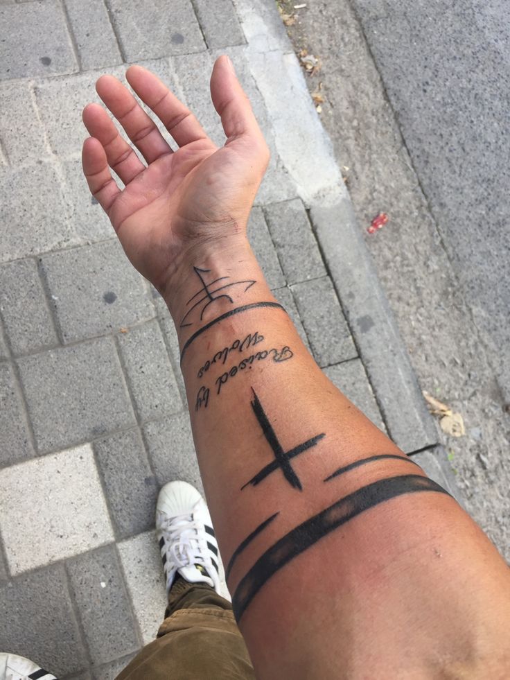 a person with a cross tattoo on their arm is holding his hand up in the air