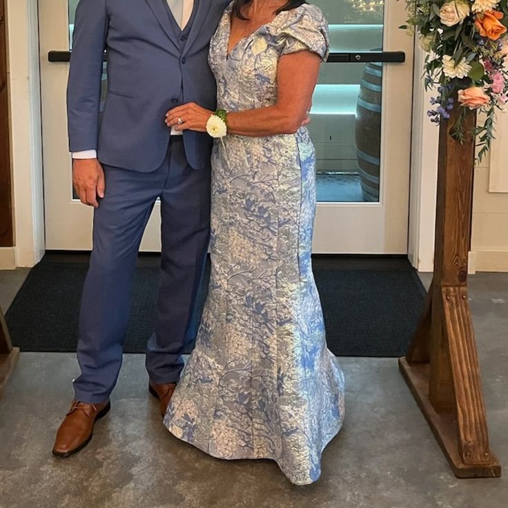 a man and woman standing next to each other in front of a doorway with flowers