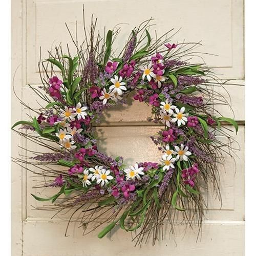 a wreath with purple and white flowers hanging on a door