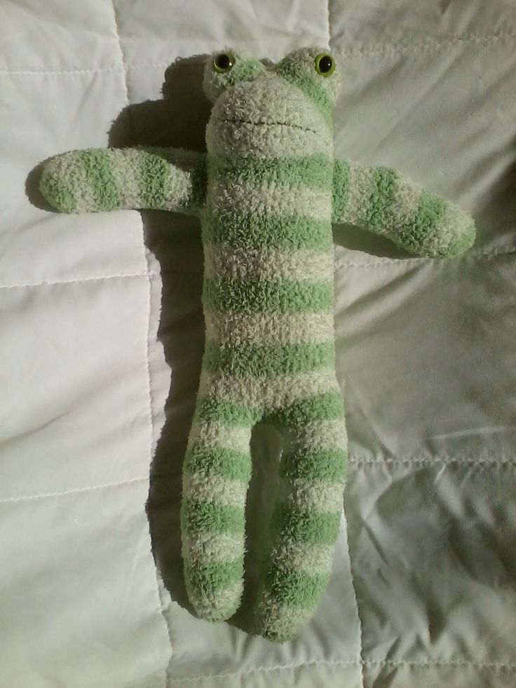 a green and white striped stuffed animal laying on a bed