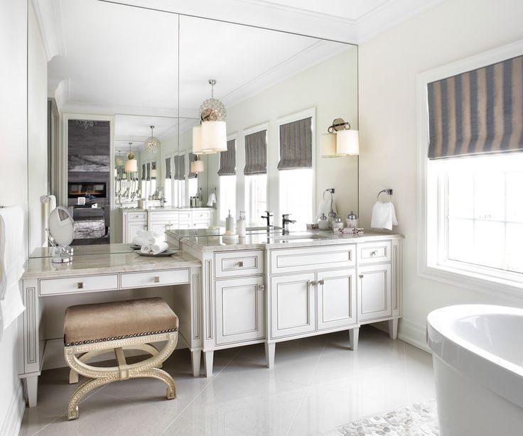 a white bathroom with two sinks and a bathtub next to a large mirror on the wall