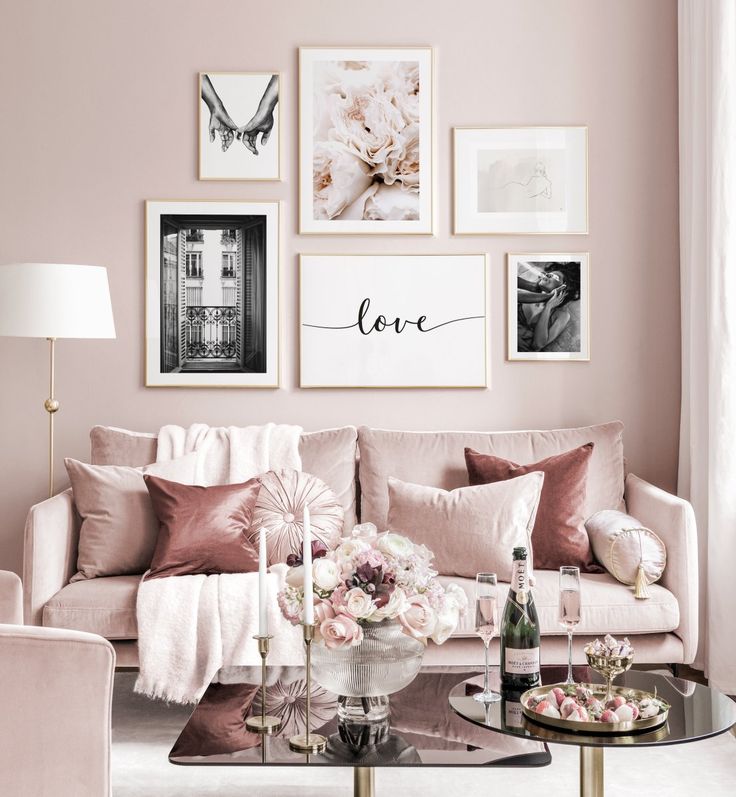 a living room with pink walls and pictures on the wall above the couch, coffee table