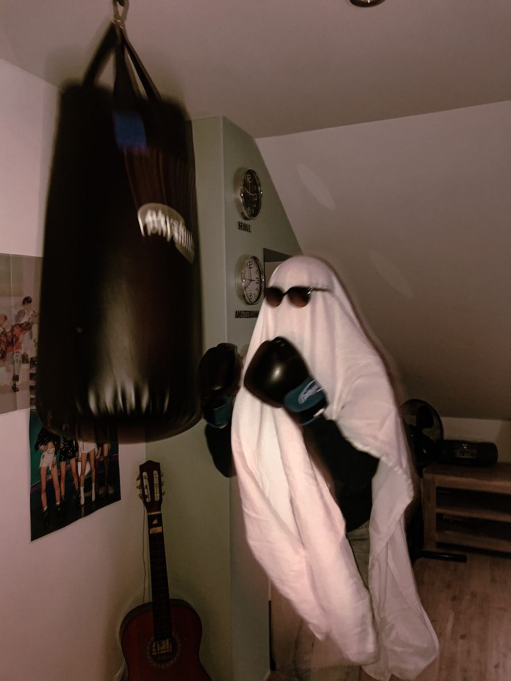 a man in a white robe and black boxing gloves hanging from a wall with a punching bag on it