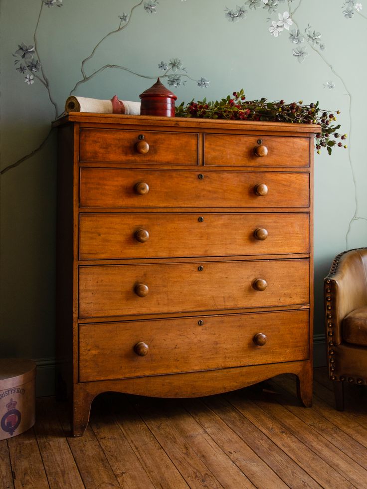 a wooden dresser sitting next to a chair in a room