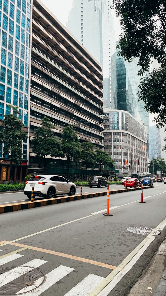 cars are parked on the side of an empty street in front of tall skyscrapers