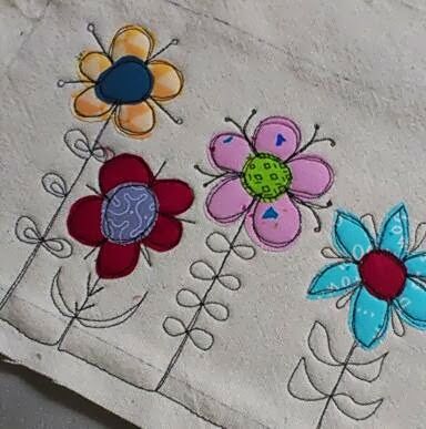 an embroidered piece of cloth with colorful flowers on it, sitting on top of a table