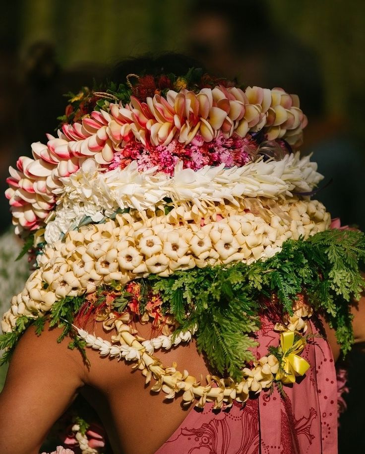 a woman with flowers on her head wearing a pink dress and flower garland around her neck