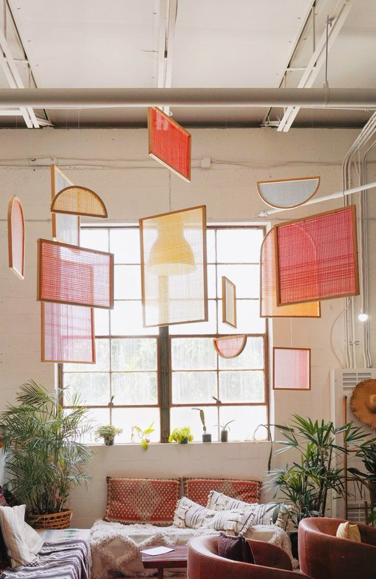 a living room filled with lots of furniture next to a large window and potted plants