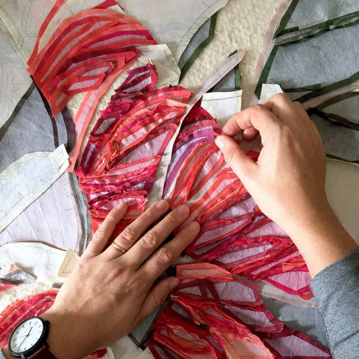 someone is working on something with red and pink strips of fabric in the shape of flowers