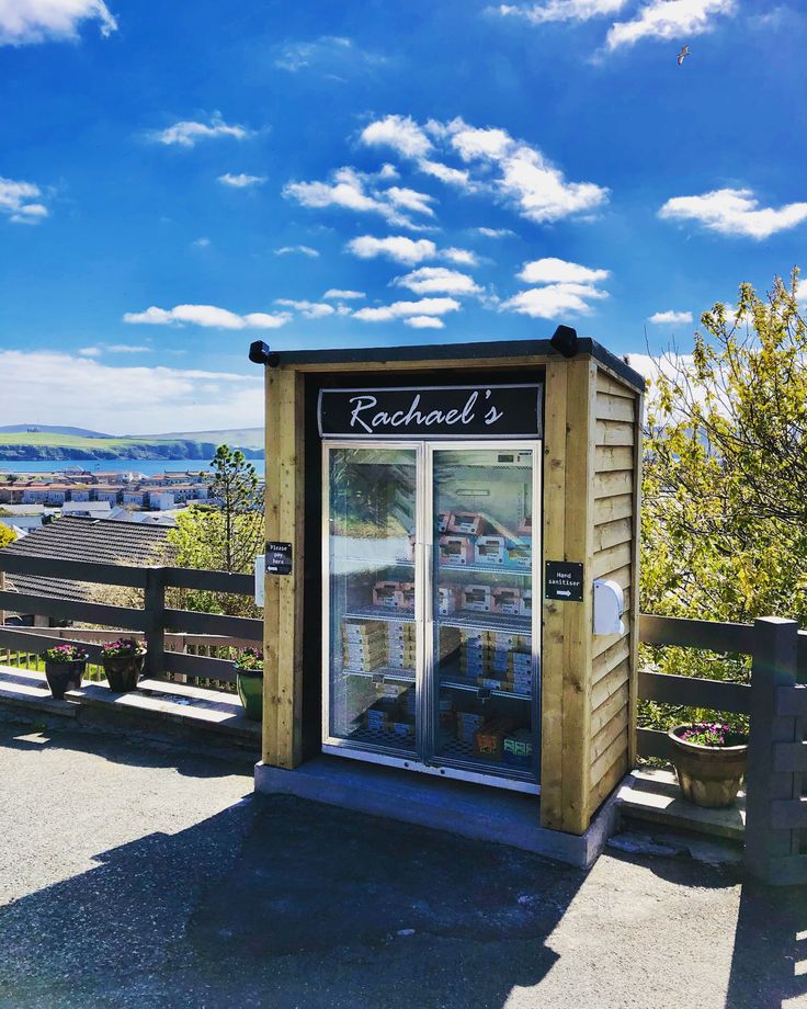 a small refrigerator sitting on top of a wooden bench in front of a blue sky