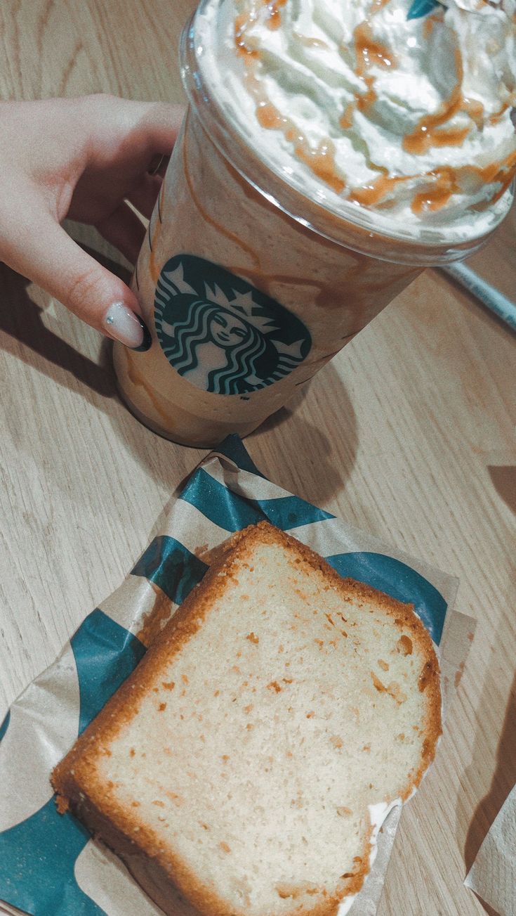 a person holding a starbucks drink over a toasted sandwich