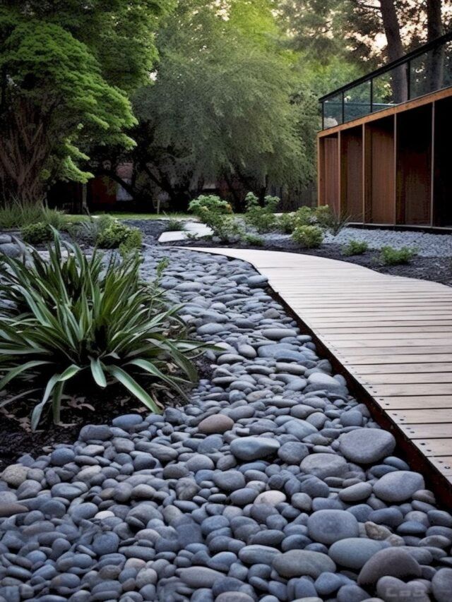 a wooden walkway surrounded by rocks leading to a building with trees and bushes in the background