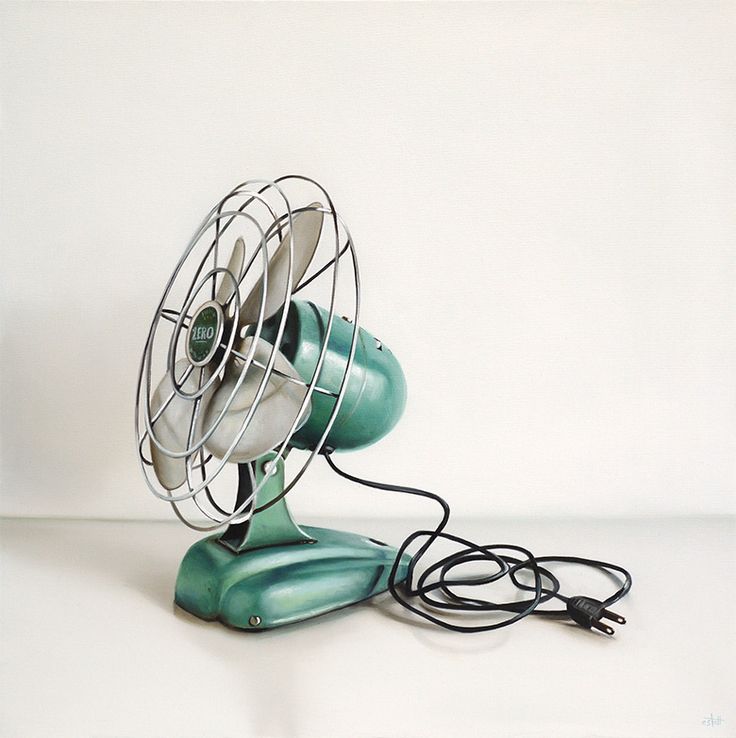 an old green fan sitting on top of a white table next to a black cord