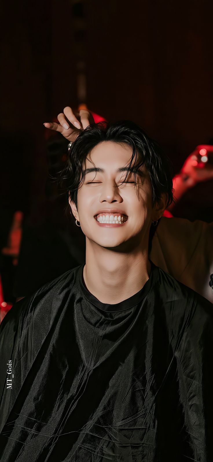 a young man smiling while getting his hair cut