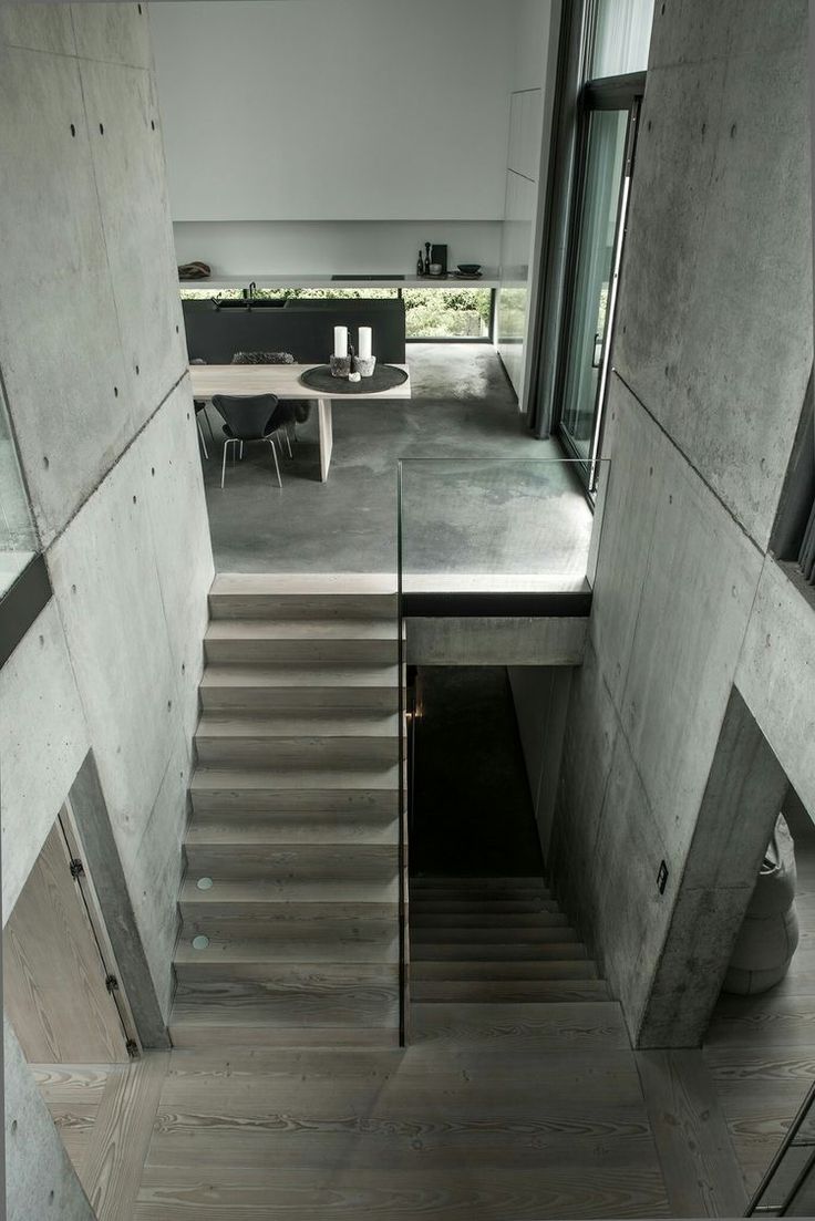 stairs lead up to the upper level of this modern house with concrete walls and flooring