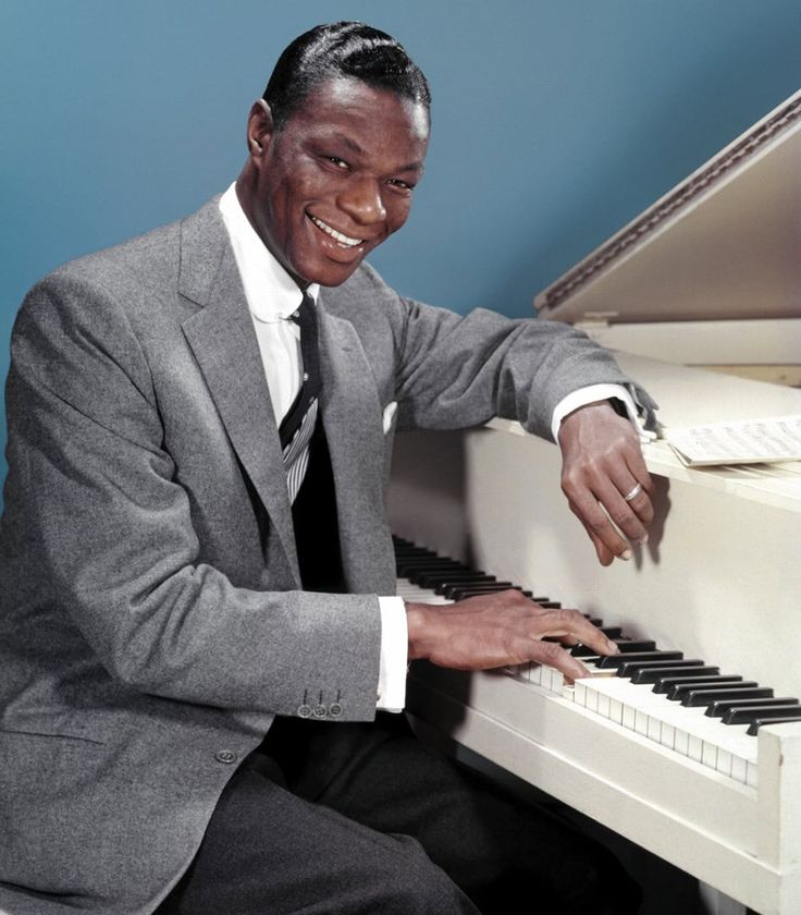 a man in a suit and tie sitting at a piano with his hand on the keys