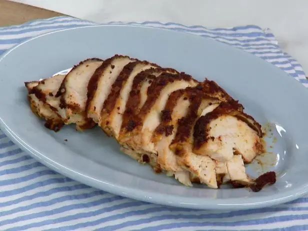 a white plate topped with sliced chicken on top of a blue and white table cloth