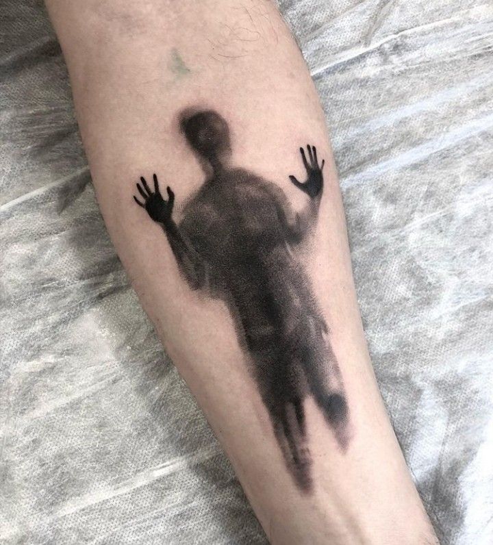 a man's arm with a black and grey ink drawing of a person on it