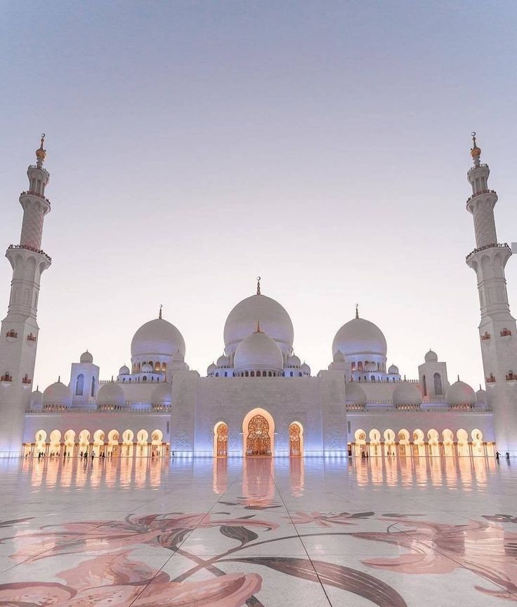 a large white building with many arches and domes on it's sides at dusk