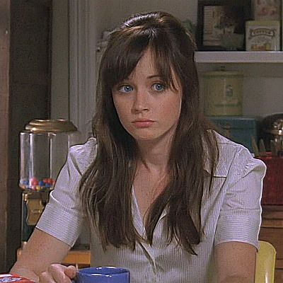 a woman sitting at a table with a blue cup