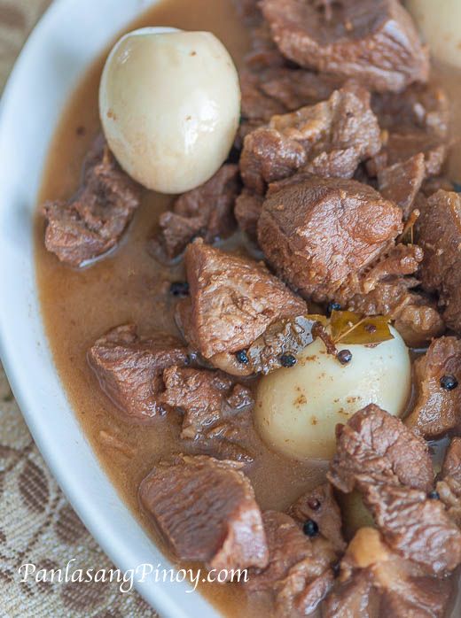 a white plate topped with meat and potatoes covered in gravy on top of a table