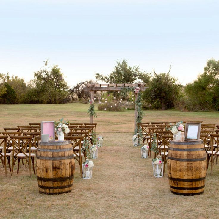 the wedding ceremony is set up outside with wine barrels and flowers in vases on the ground