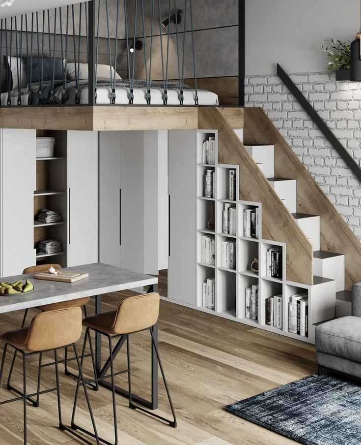 a living room and dining area with bookshelves in the middle, stairs leading up to the second floor