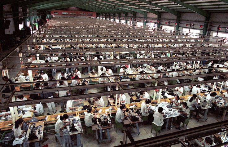 an industrial factory with lots of workers working on machines and people sitting at desks