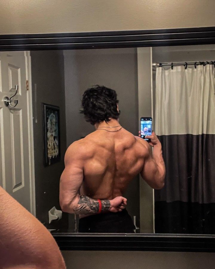 a man taking a selfie in front of a mirror with his back turned to the camera