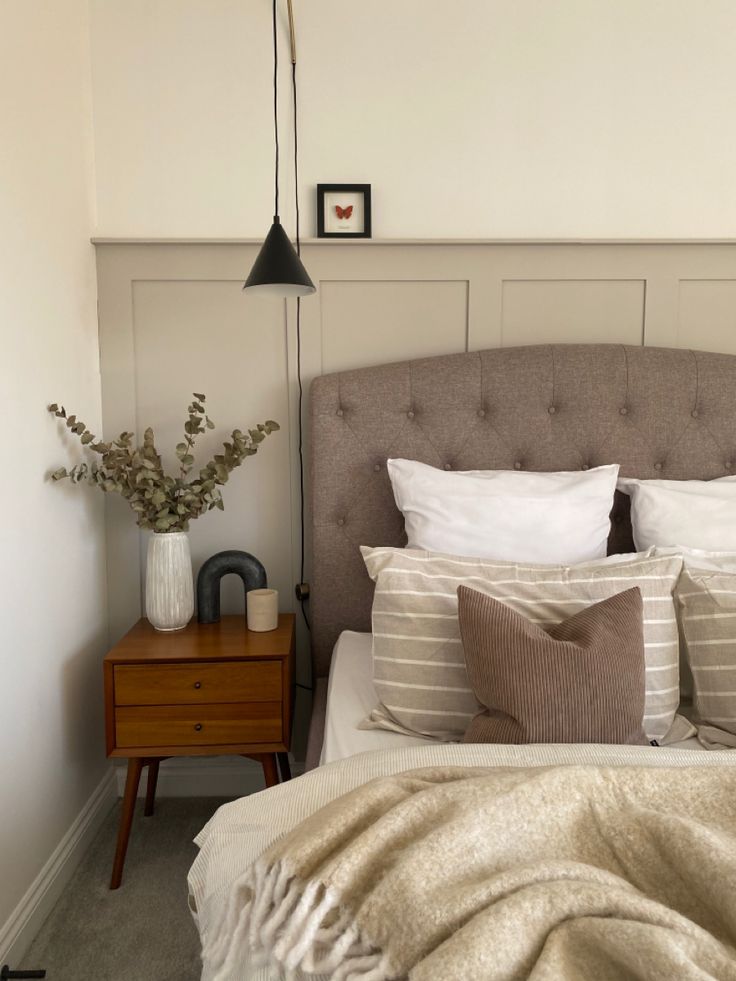 a bedroom with a bed, nightstand and lamp on the side table in front of it