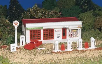 a toy gas station with red roof and white fence