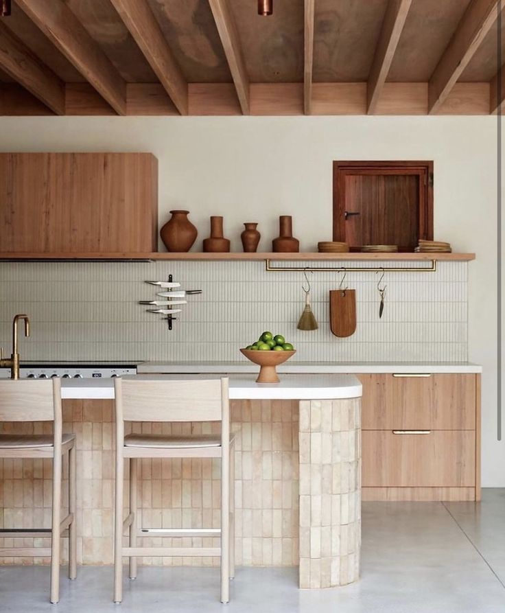 a kitchen with wooden cabinets and white counter tops, two stools at the island