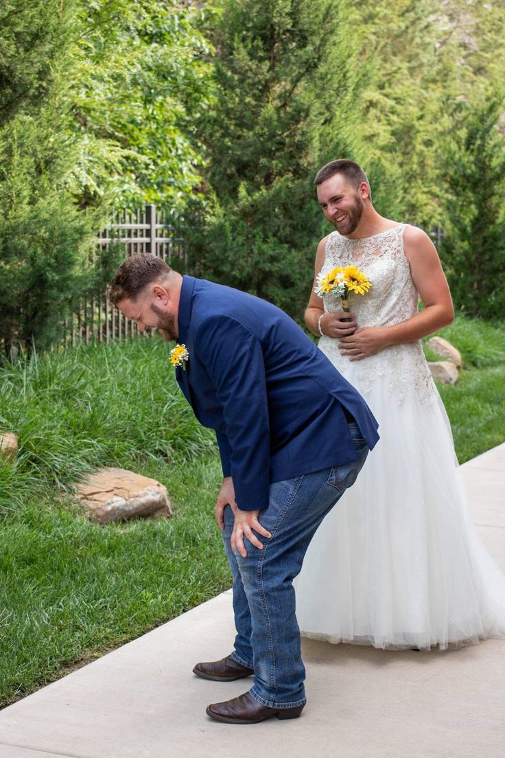 a man kneeling down next to a woman in a white dress and yellow flowers on her wedding day