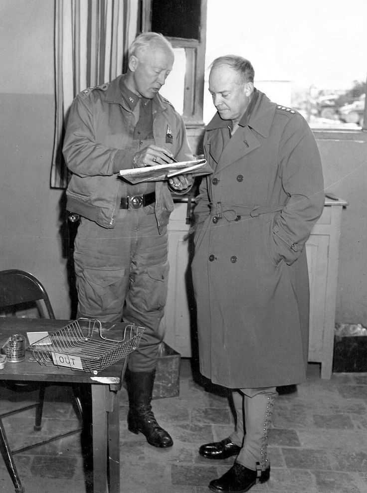 two men standing next to each other looking at something on a table in front of them